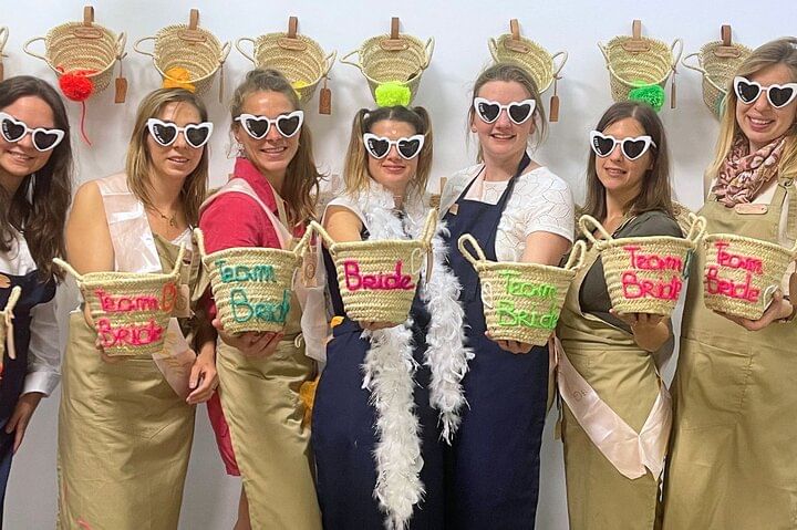 Group of young women in costumes and sunglasses holding their personalized hats during a fun bachelorette embroidery workshop in Marrakech.