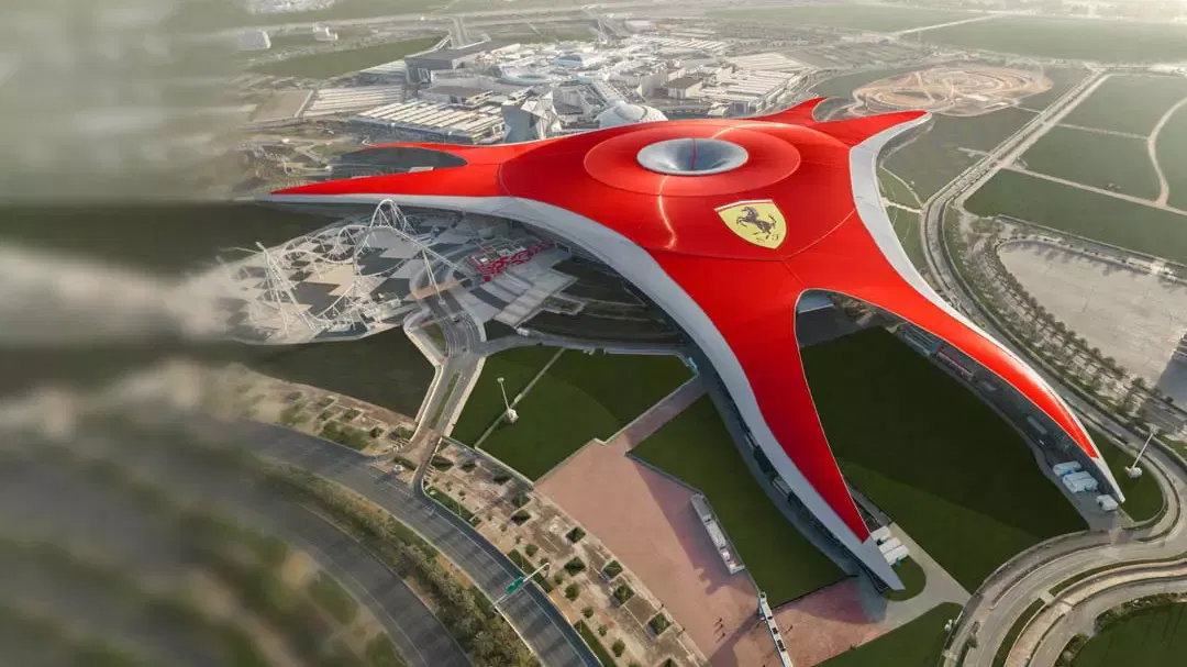 Aerial view of the vast red star-shaped roof of the park with the yellow Ferrari shield at its centre, at Ferrari World Abu Dhabi