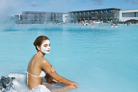 Woman relaxes in the Blue Lagoon Iceland spa with a face mask