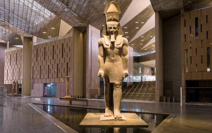 Grand Egyptian Museum exterior with visitors entering the modern glass building near the Giza Plateau.