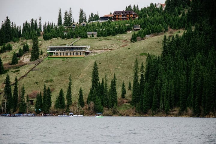 Blue alpine lake in Kazakhstan with pine-covered mountains and scenic shoreline.