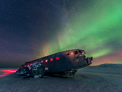 The Northern Lights over the plane wreck at Solheimasandur