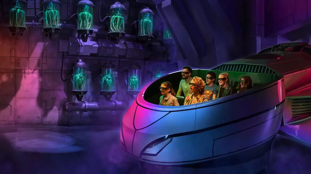 Six people wearing 3D glasses ride in a futuristic vehicle past glowing specimen jars at Warner Bros. World Abu Dhabi Theme Park.