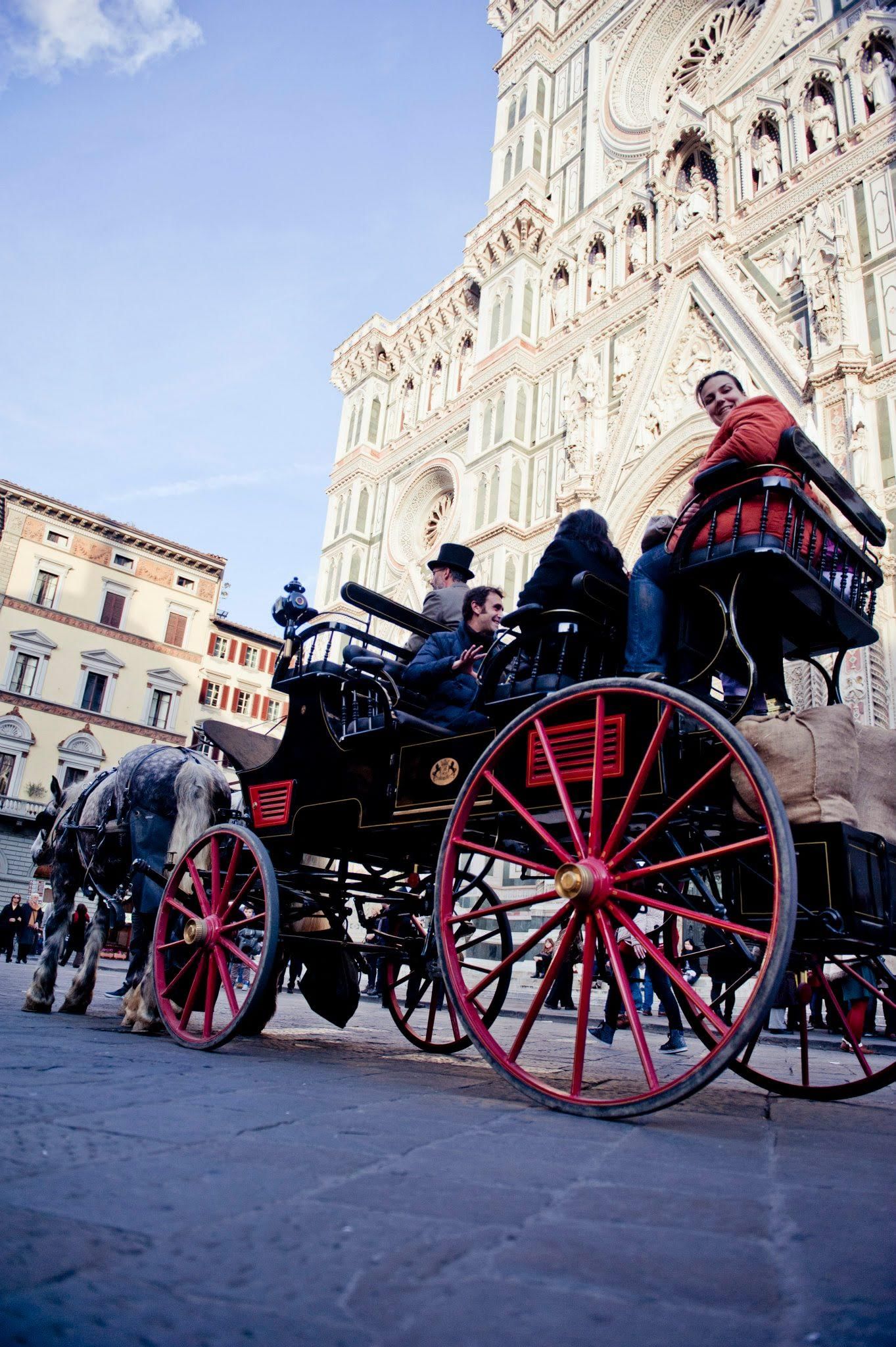 Side view of a carriage with passengers in Duomo Square in front of the Cathedral