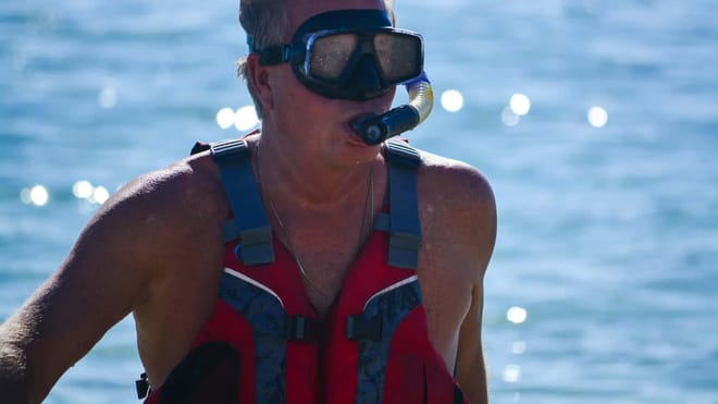 Guest wearing snorkel gear and life vest during a beach snorkeling tour in Los Cabos