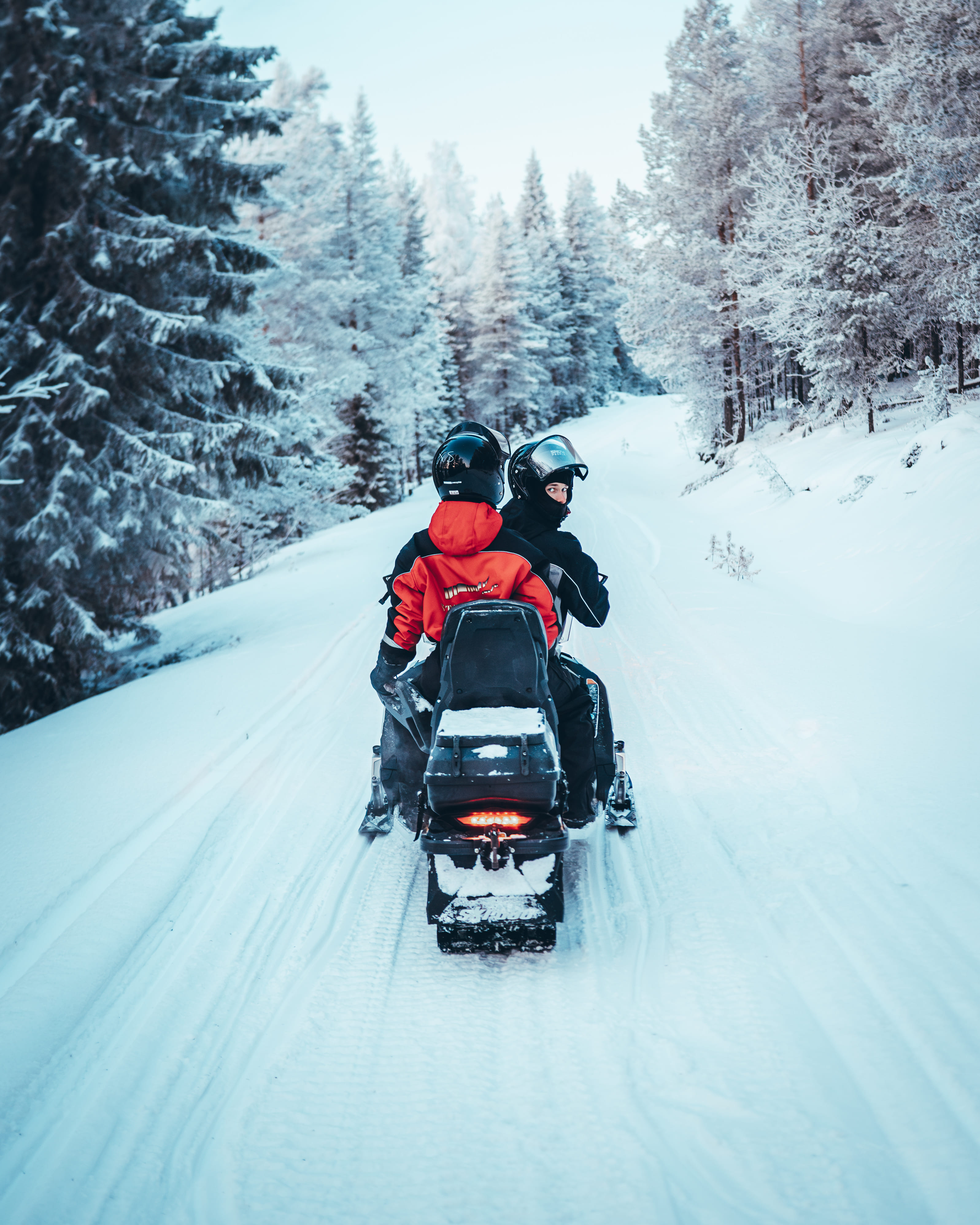 Two guests riding a snowmobile together during StayLapland’s Kuoksa Husky & Snowmobile Adventure in the snowy landscape of Rovaniemi.