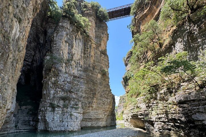 Tall limestone cliffs of Osumi Canyon with a bridge crossing above.