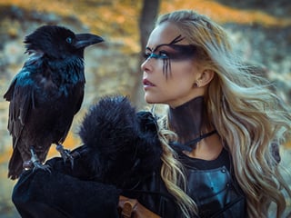 A viking woman holding a crow on her arm