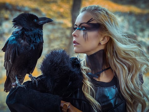 A viking woman holding a crow on her arm