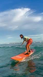 A girl attempting to stand up on a surfboard during a surf course in Fuvahmulah.