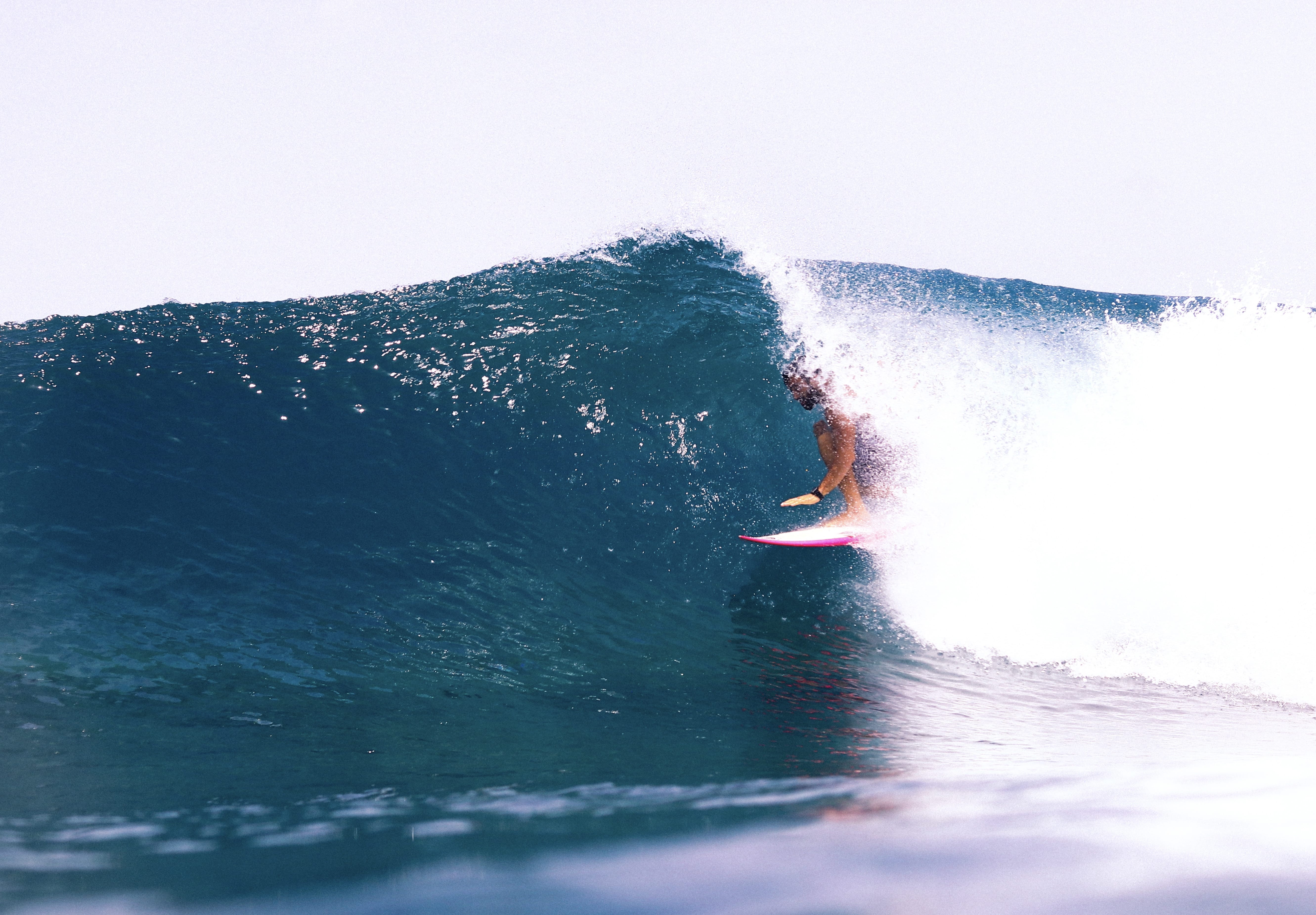 A man enjoying barrel surfing at one of the Northern Atolls' surf breaks in the Maldives, with crystal-clear water and stunning wave formati