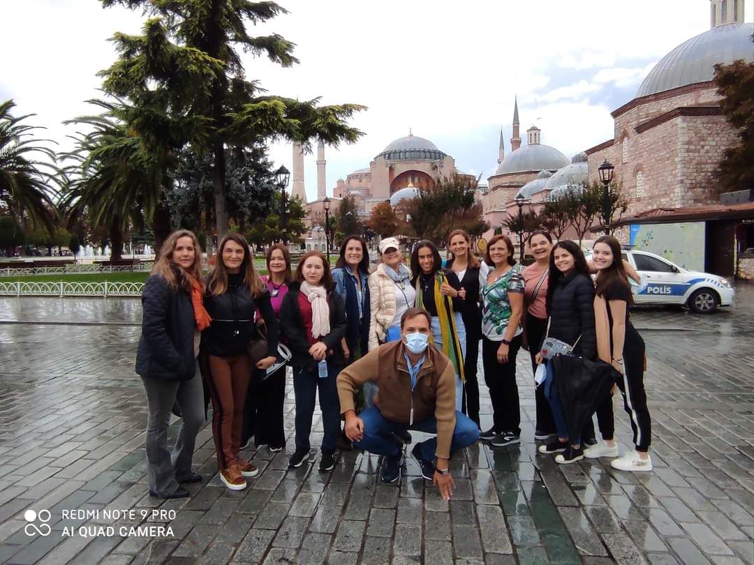 “A tour guide and a smiling group of travelers posing in Sultanahmet Square with the Hagia Sophia visible behind them under a clear sky.”
