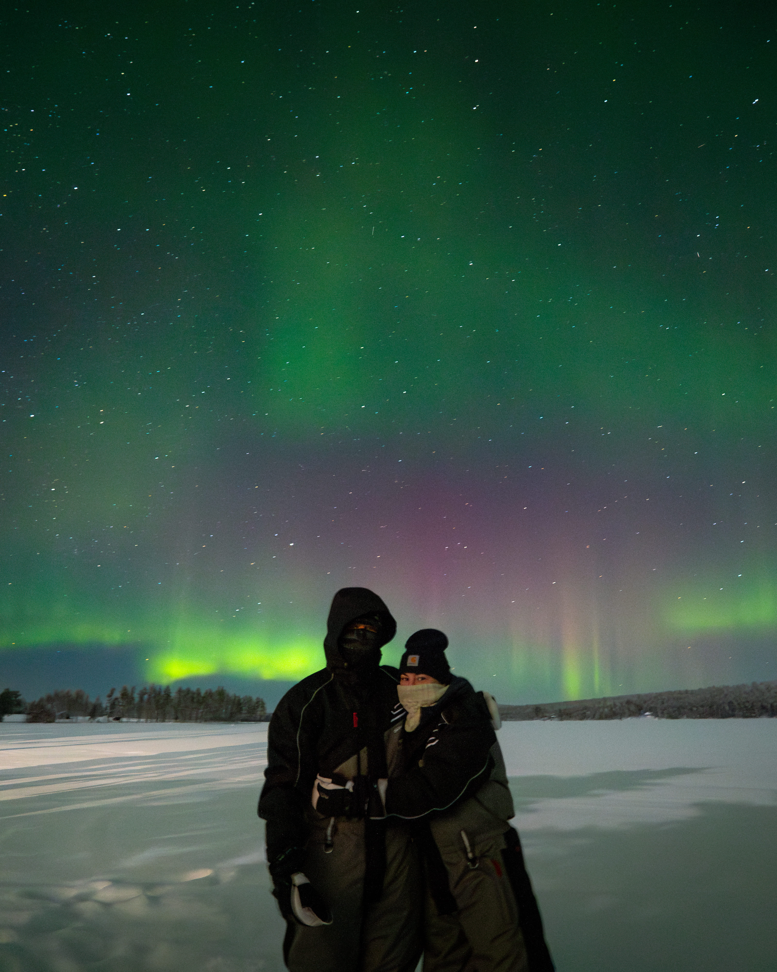 A couple watches the Northern Lights at StayLapland, creating magical moments during a campfire Northern Lights adventure in Rovaniemi.