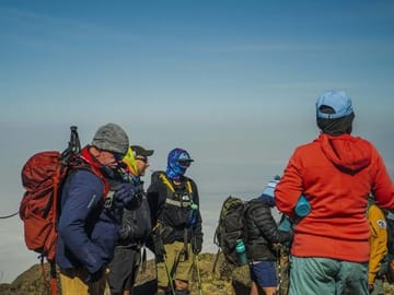 Trekkers taking a moment to rest and enjoy the mountain views during a Kilimanjaro climb.