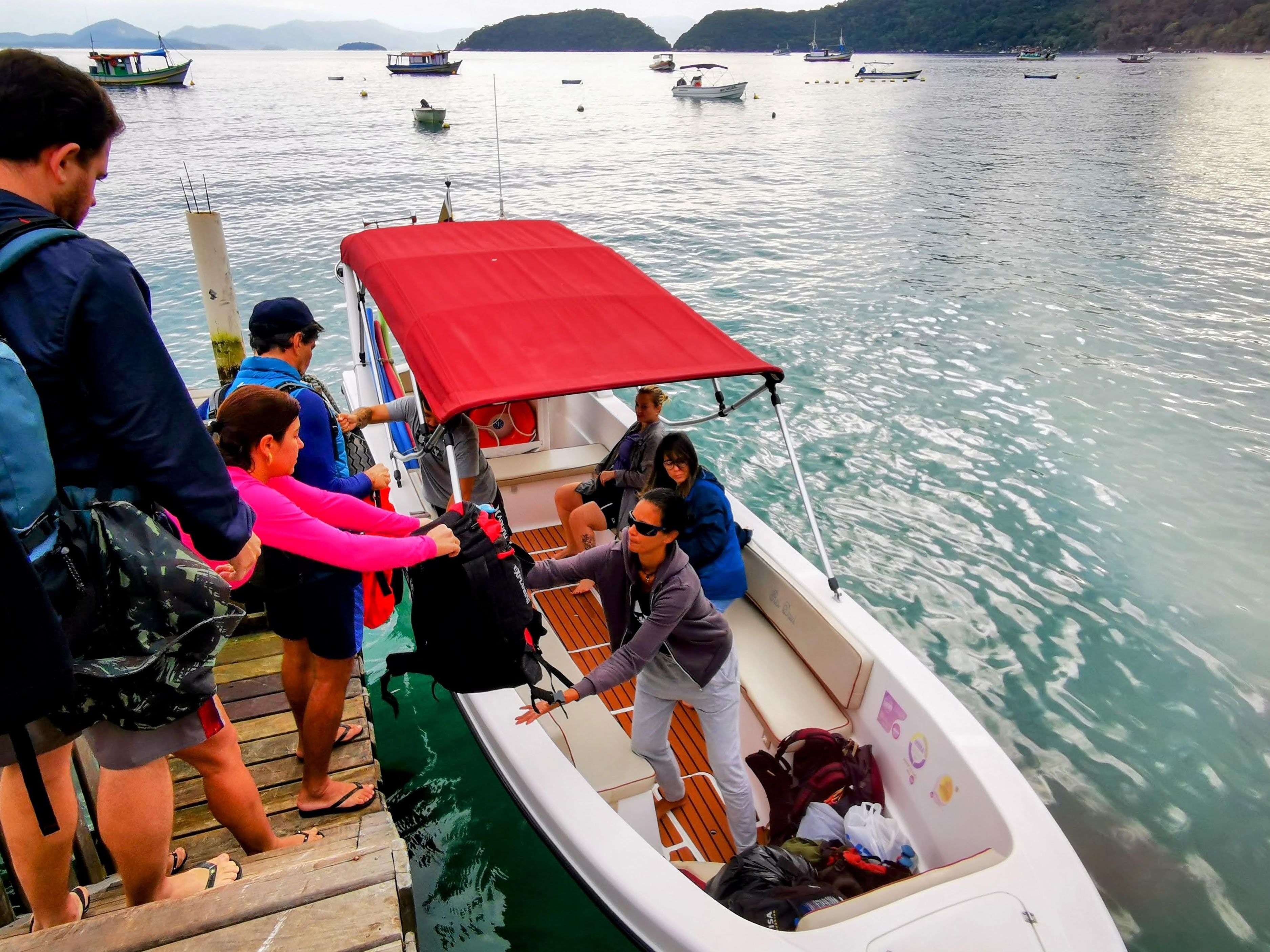Viajantes embarcando em um barco particular no píer, Ilha Grande, ilustrando o tipo de embarcação usada para a opção de barco particular