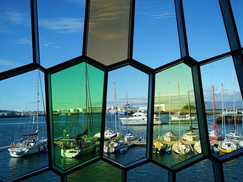 Reykjavík's Old Harbor with boats shot from the inside of Harpa, with its colored glass in the facade