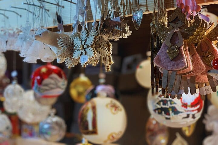 Gold, red, white Christmas decorations, including a polar bear, angels, and snowflakes, suspended inside a market chalet.
