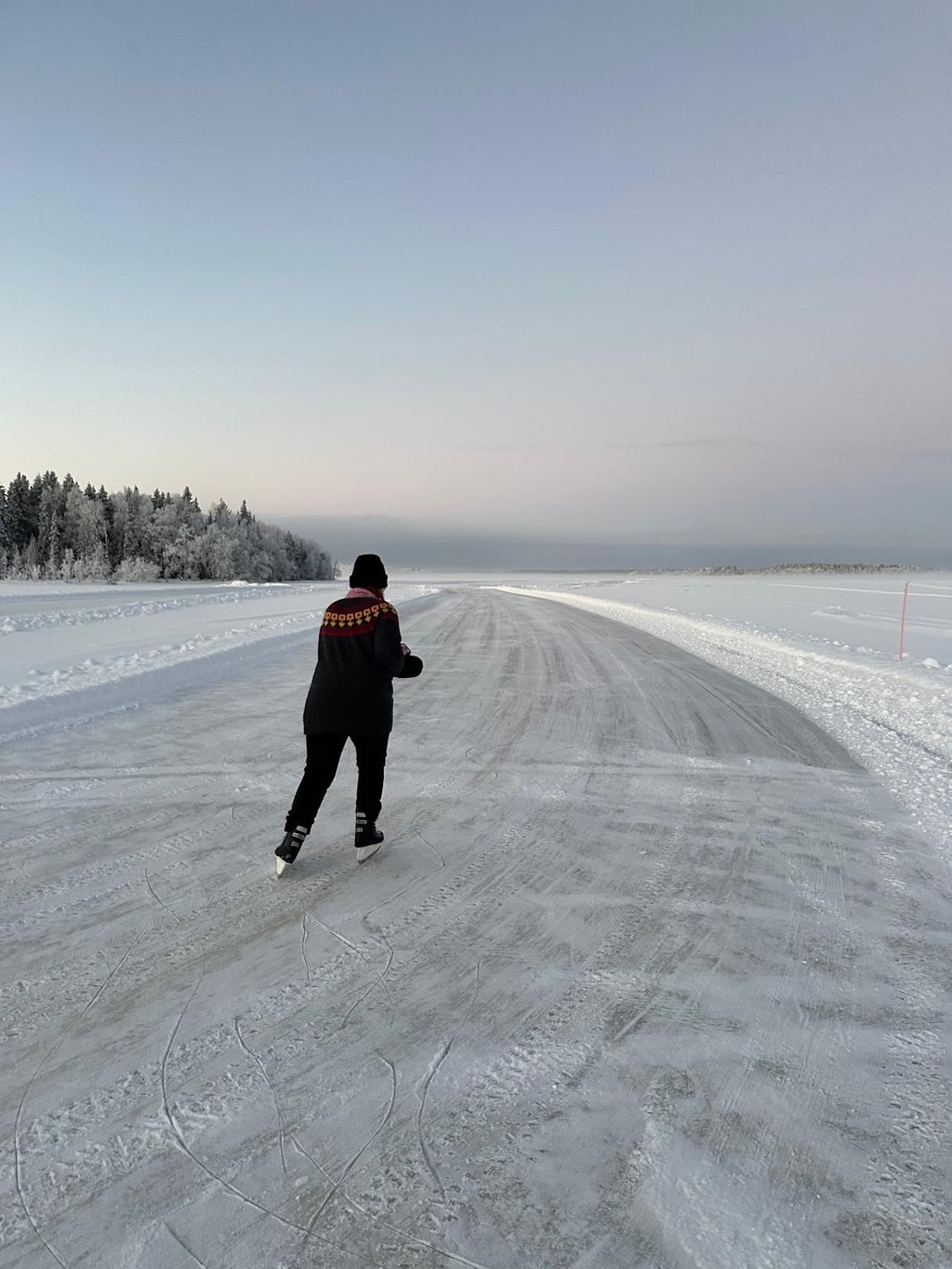 A visitor tour skating on the cleared ice track of frozen Rautusjärvi near Arctic Village