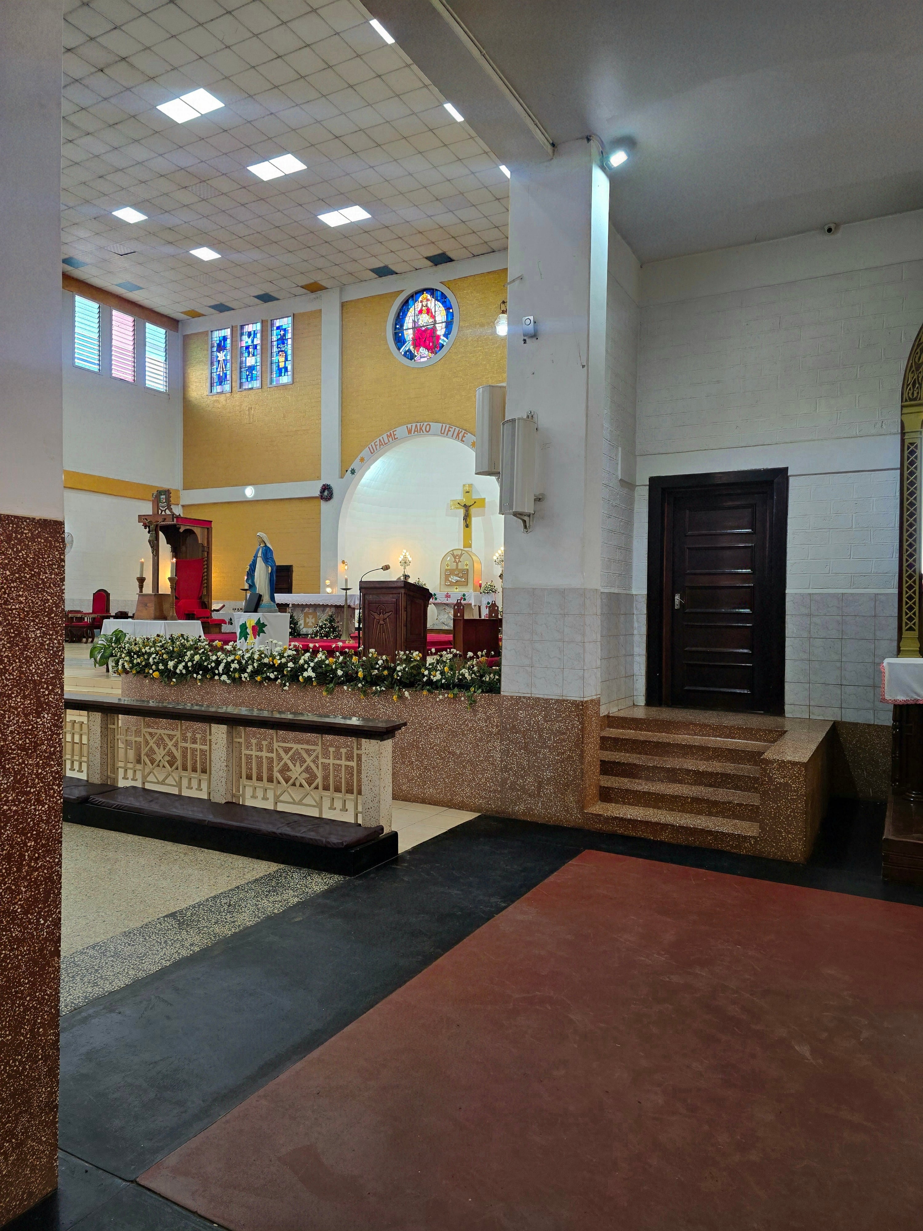 A side perspective of the elevated altar platform and communion rail area inside Christ the King Cathedral in Moshi.