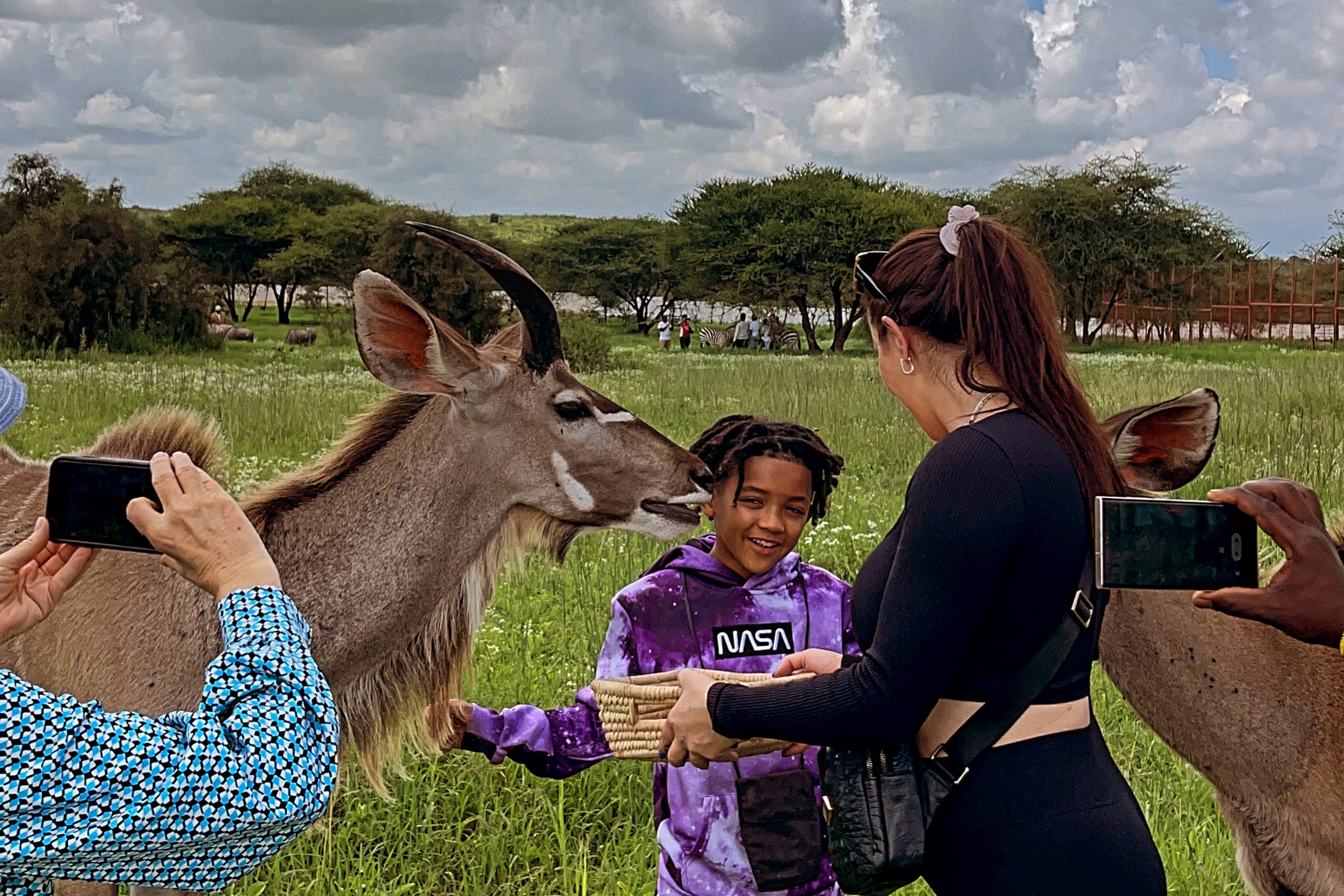 ​A mother and child enjoying a private wildlife encounter with a Kudu in a secure sanctuary.