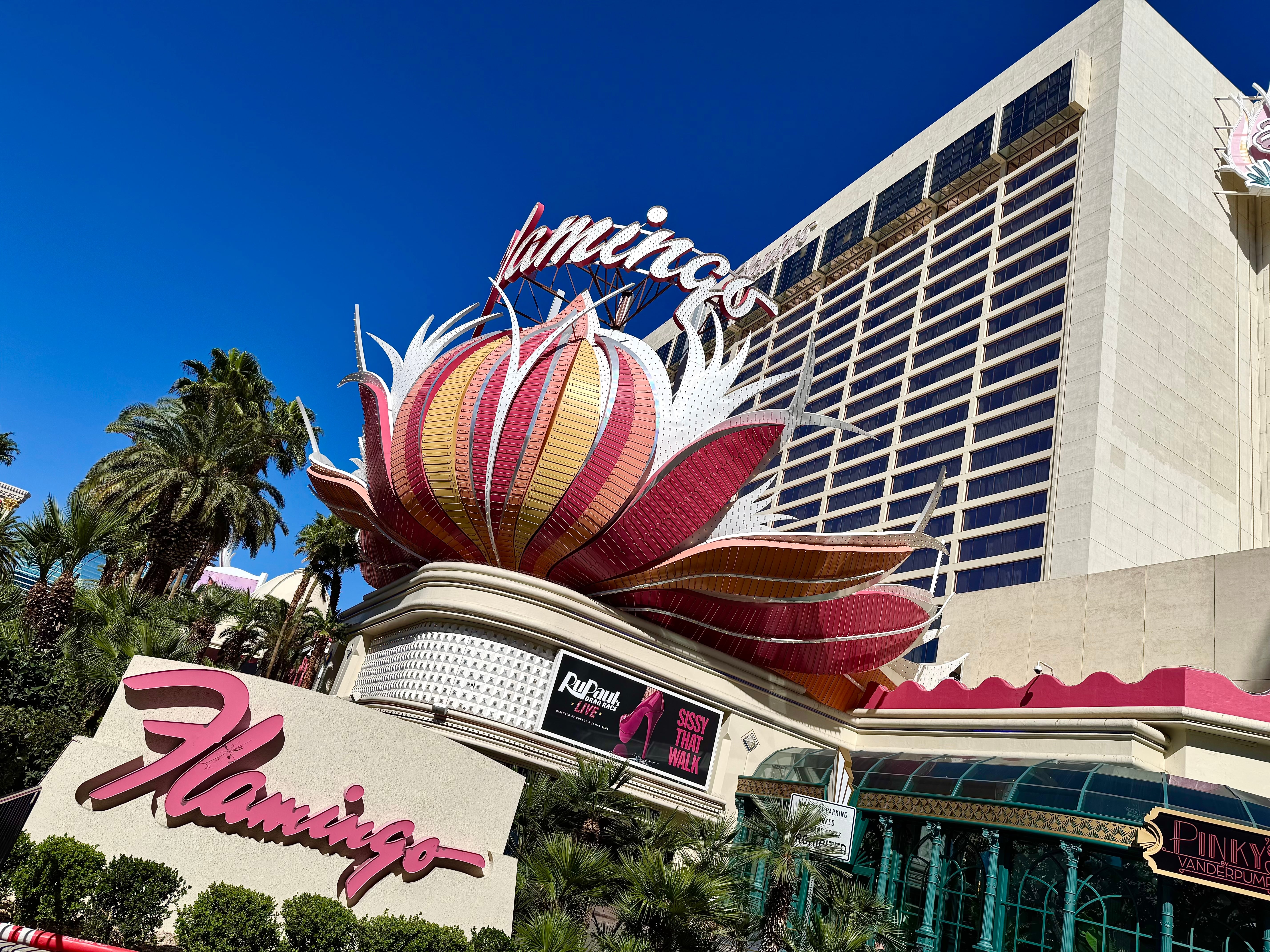 The Flamingo hotel and its pink neon roadside sign beneath a bright blue sky.