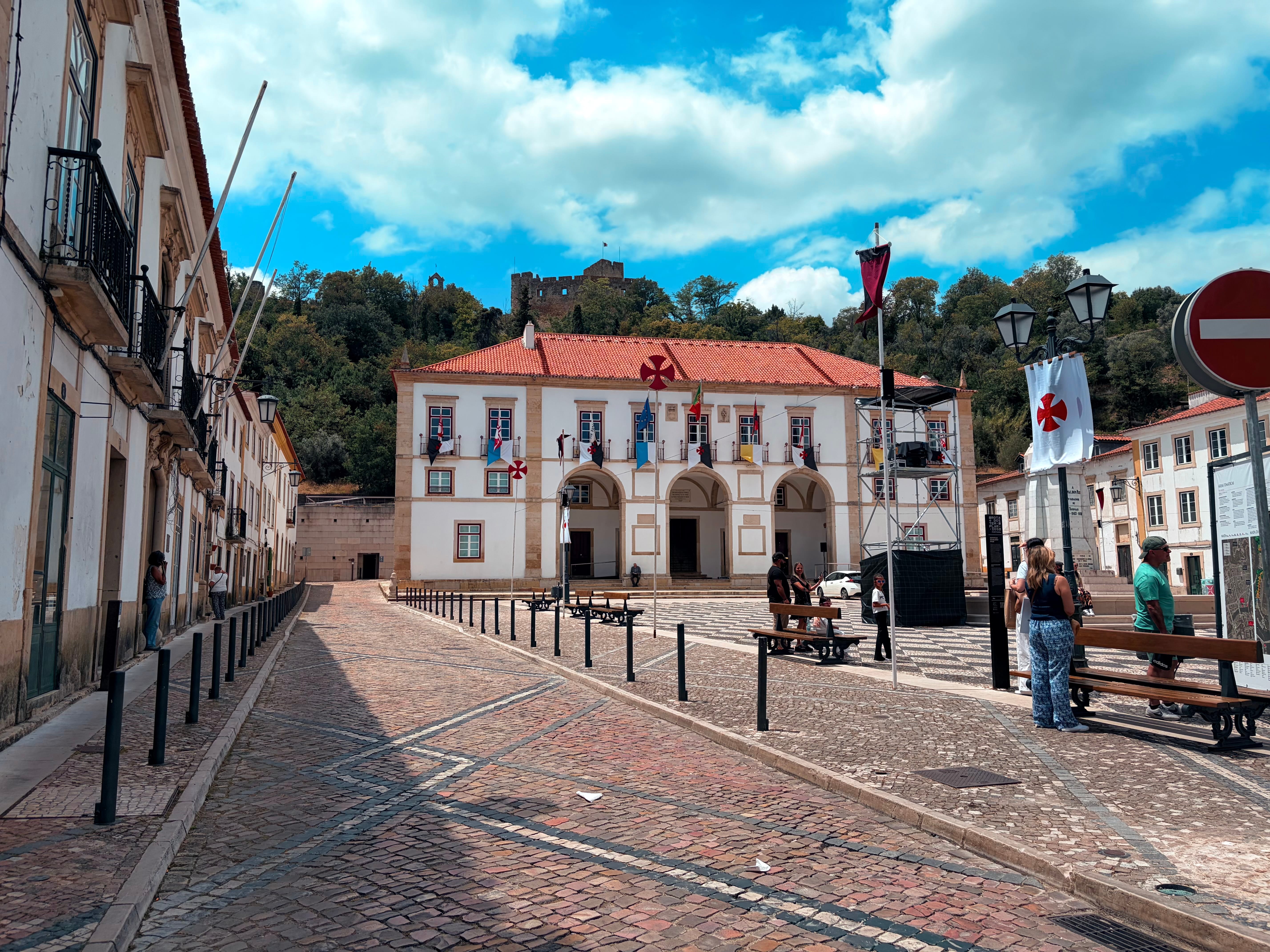 Rua pedonal no centro histórico de Tomar, com paralelepípedos tradicionais, edifícios históricos de fachadas coloridas e esplanadas de cafés