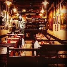 A cozy and warmly lit bouchon lyonnais with red-checkered tablecloths, wooden decor, and a welcoming atmosphere, ready to serve traditional