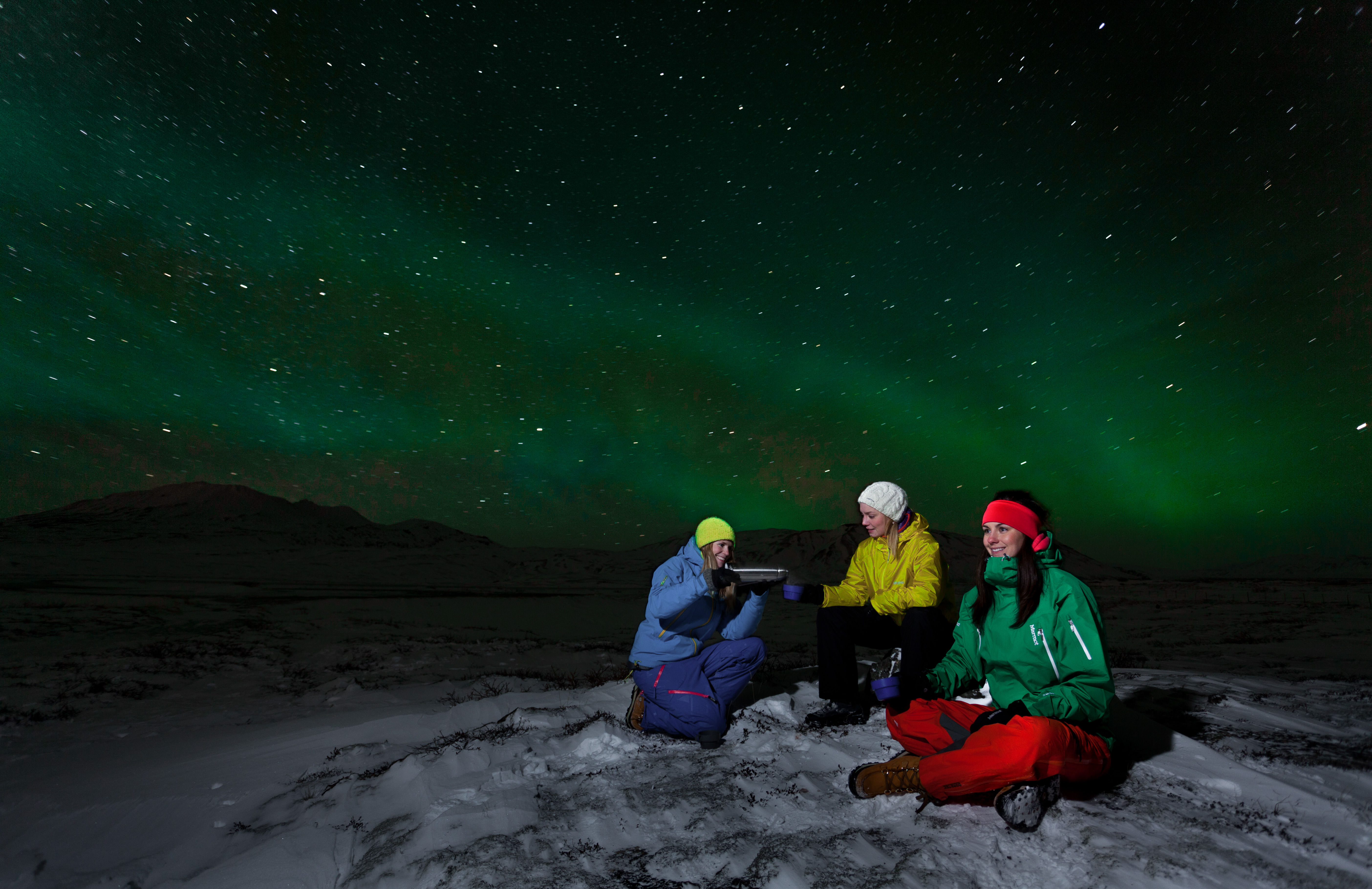 Three people enjoying the skies during Arctic adventures northern lights tour