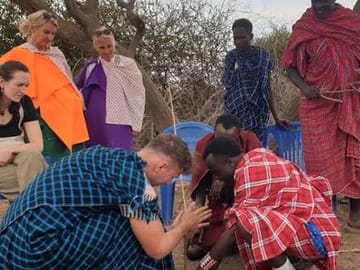 Guests learning traditional fire-making techniques with Maasai hosts in Tanzania.