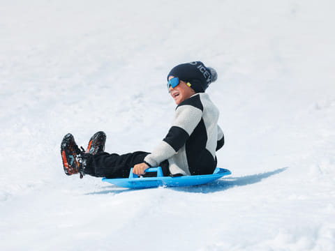 Child sledding down a snowy slope