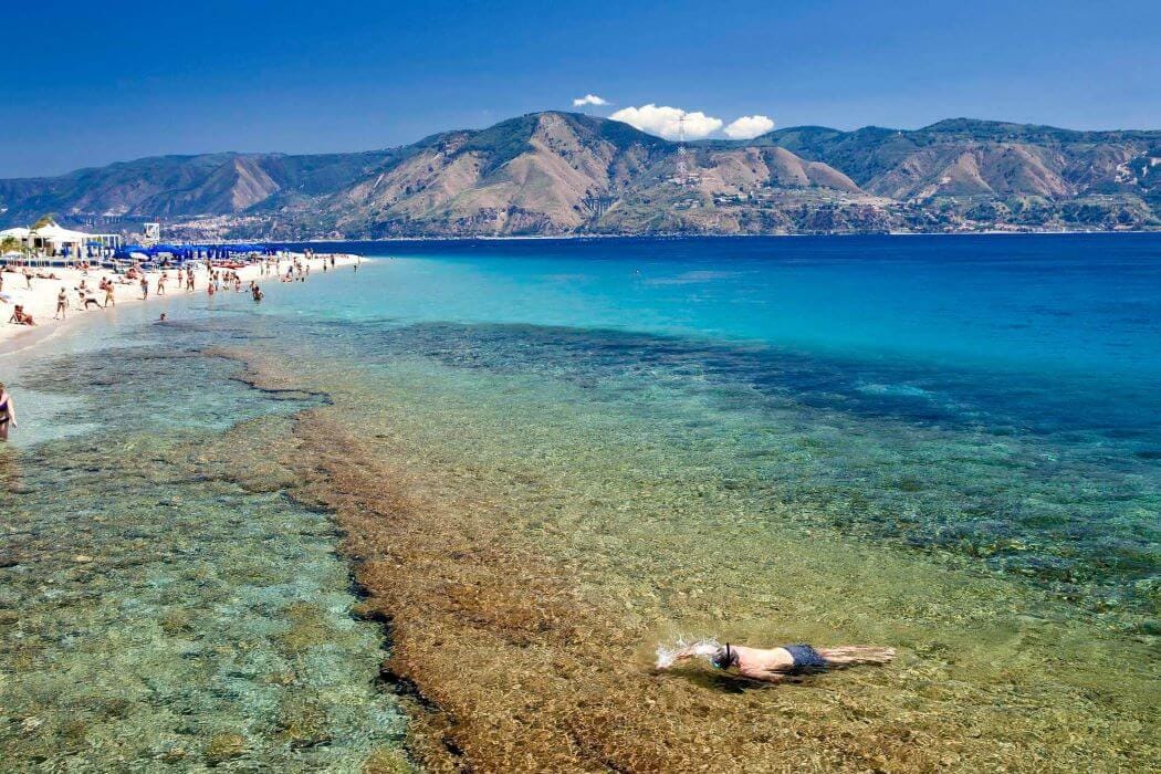 People swimming and relaxing on Capo Peloro beach