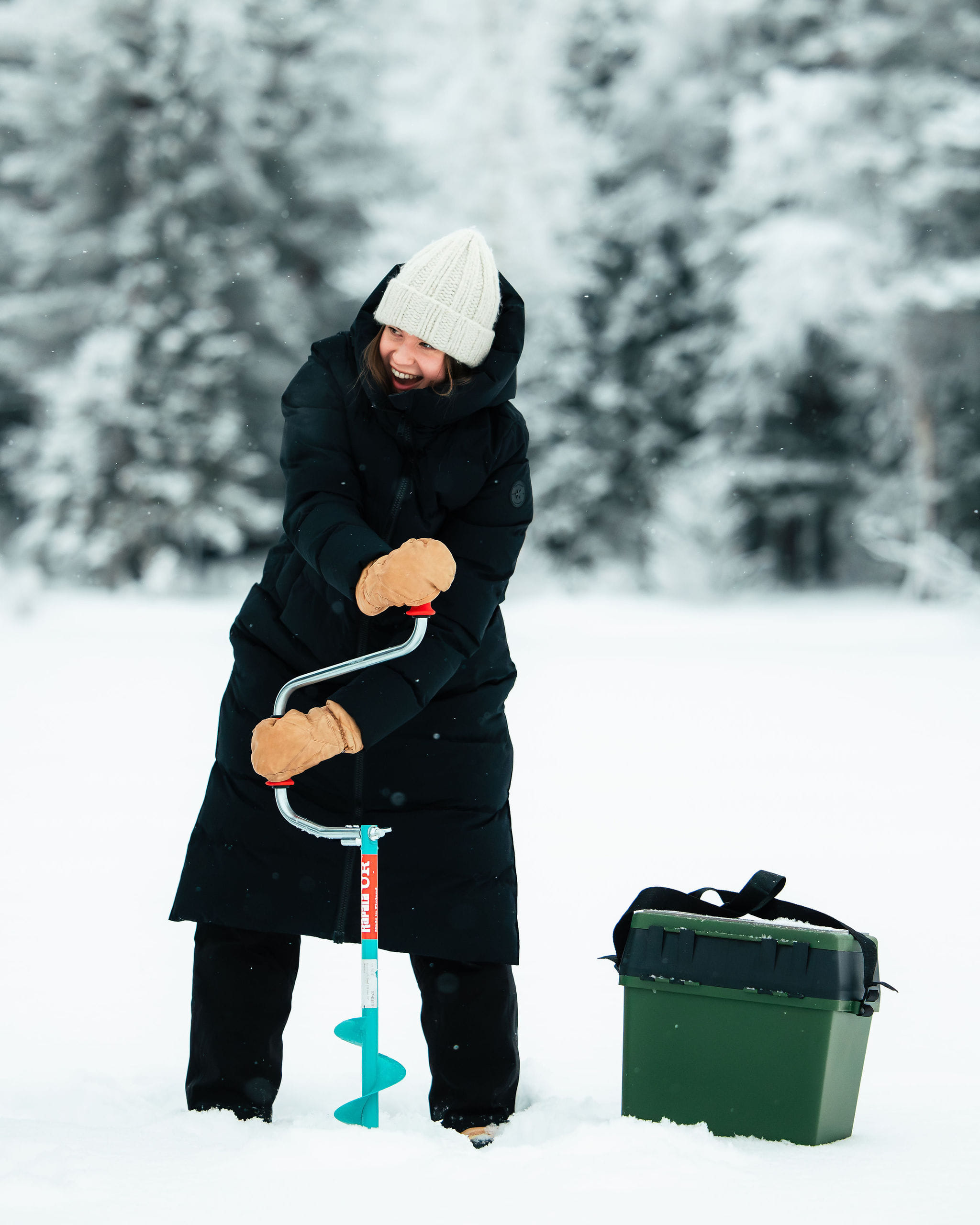 A woman drilling ice fishing hole