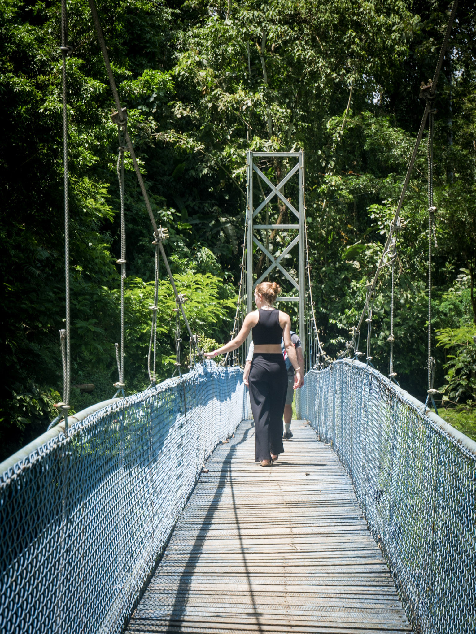 Visitors crossing a suspension bridge surrounded by tropical rainforest on the way to the Bribri Indigenous community of Yorkín, Costa Rica.
