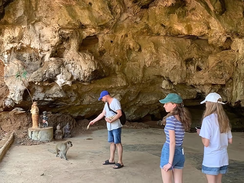Visitors in the monkey temple cave with a macaque nearby