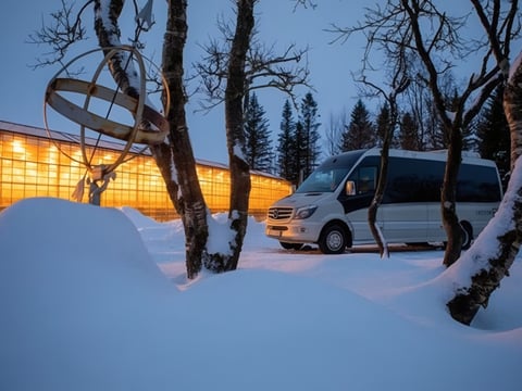 Snow-covered Friðheimar tomato farm with bright greenhouse lights glowing in winter