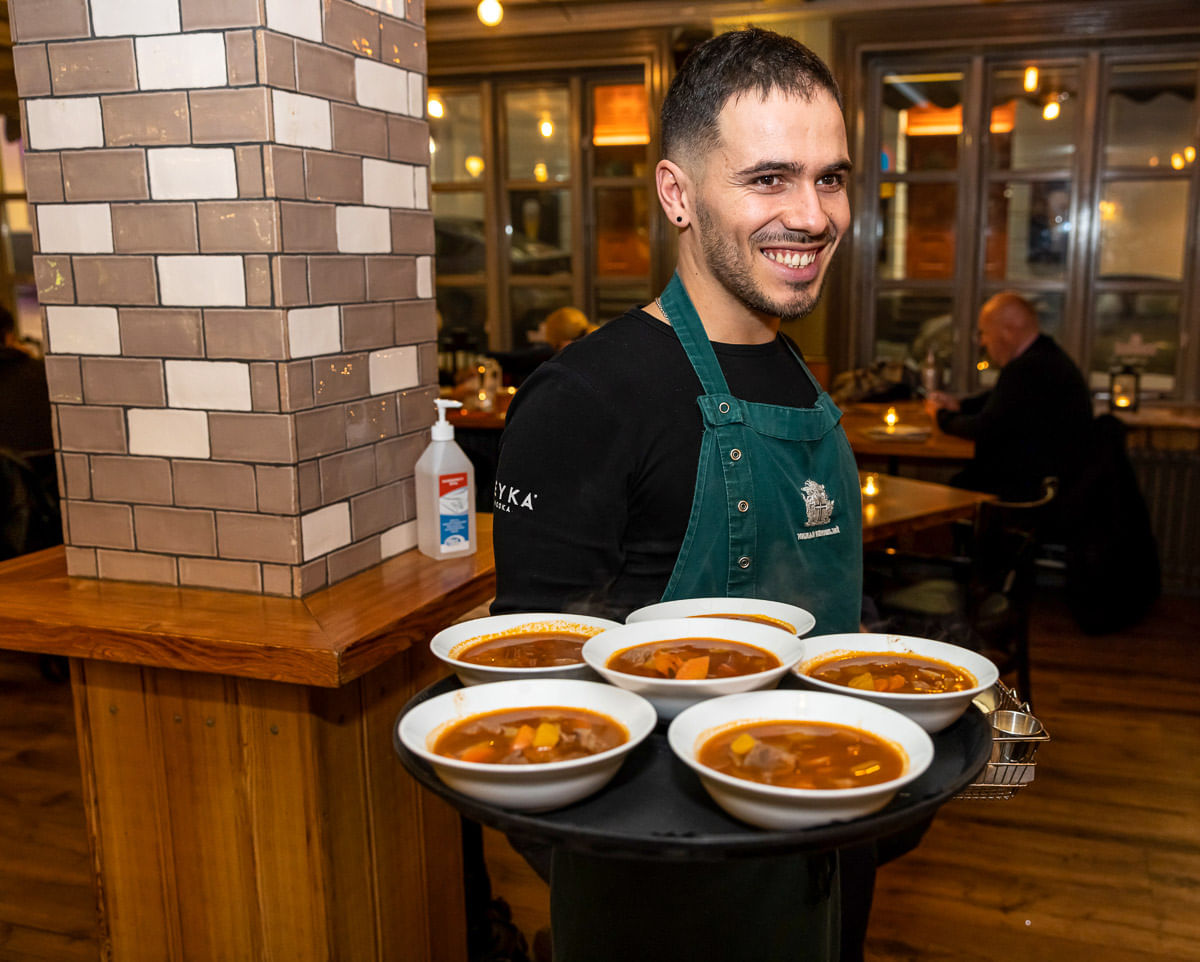 A waiter carrying plates of Icelandic Meat Soup