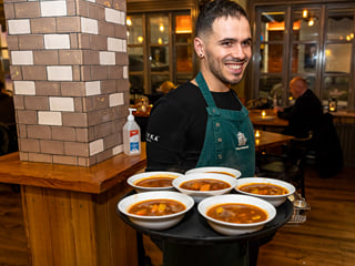 A waiter carrying plates of Icelandic Meat Soup