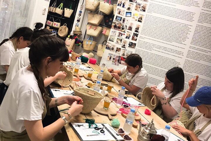 Tourists learning Moroccan embroidery in Arabic calligraphy at the Original Marrakech workshop.