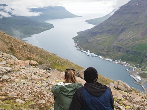 A couple enjoying the view of a valley from on top of a hill