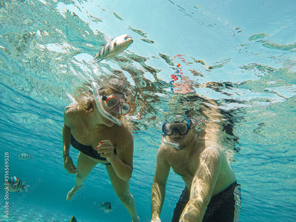 Romantic couple enjoying snorkeling with Maxie Sailing at blue waters of Fuik Bay