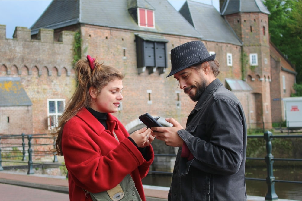 Players using their phones in front of the Koppelpoort during the Amersfoort escape game by Qugato.