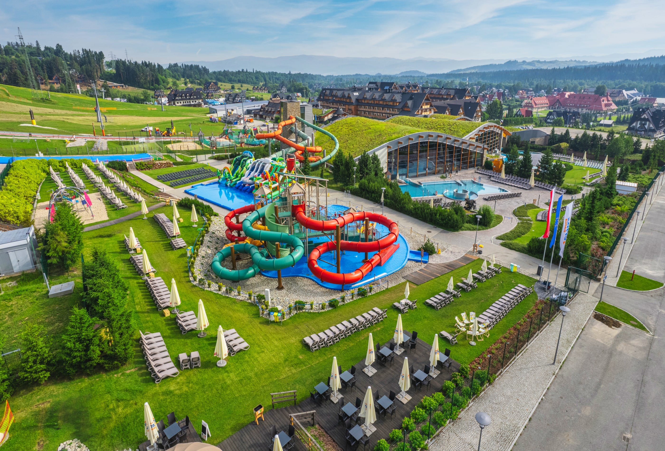 Aerial view of Terma Bania Białka Tatrzańska thermal complex with multiple outdoor pools and sun loungers in summer