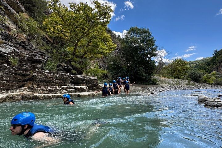 Groups of people navigating a canyon river , surrounded by towering canyon walls and clear water .