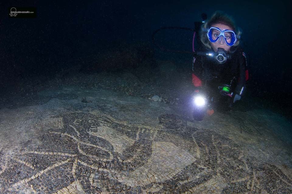 Diver swimming near the black and white mosaic from the 