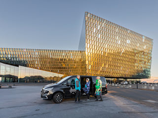 A tour group in front of a Your Friend in Reykjavik tour vehicle at the Harpa Concert Hall in Reykjavik.
