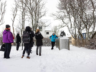 A guide from Your Friend in Reykjavik in front of a monument sharing a story.