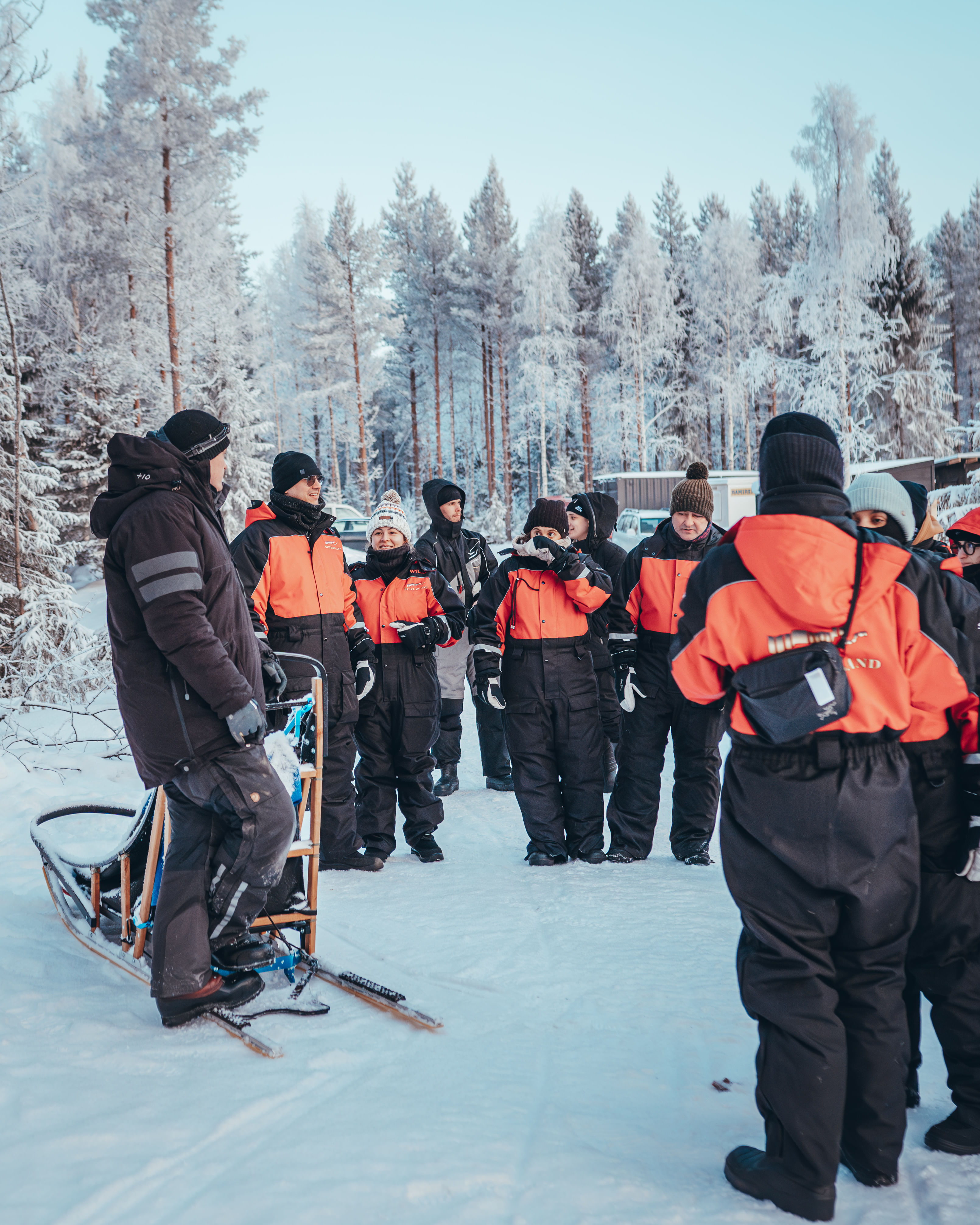 Guests in winter suits attending the Kuoksa Husky & Reindeer Adventure, led by a guide in Rovaniemi.