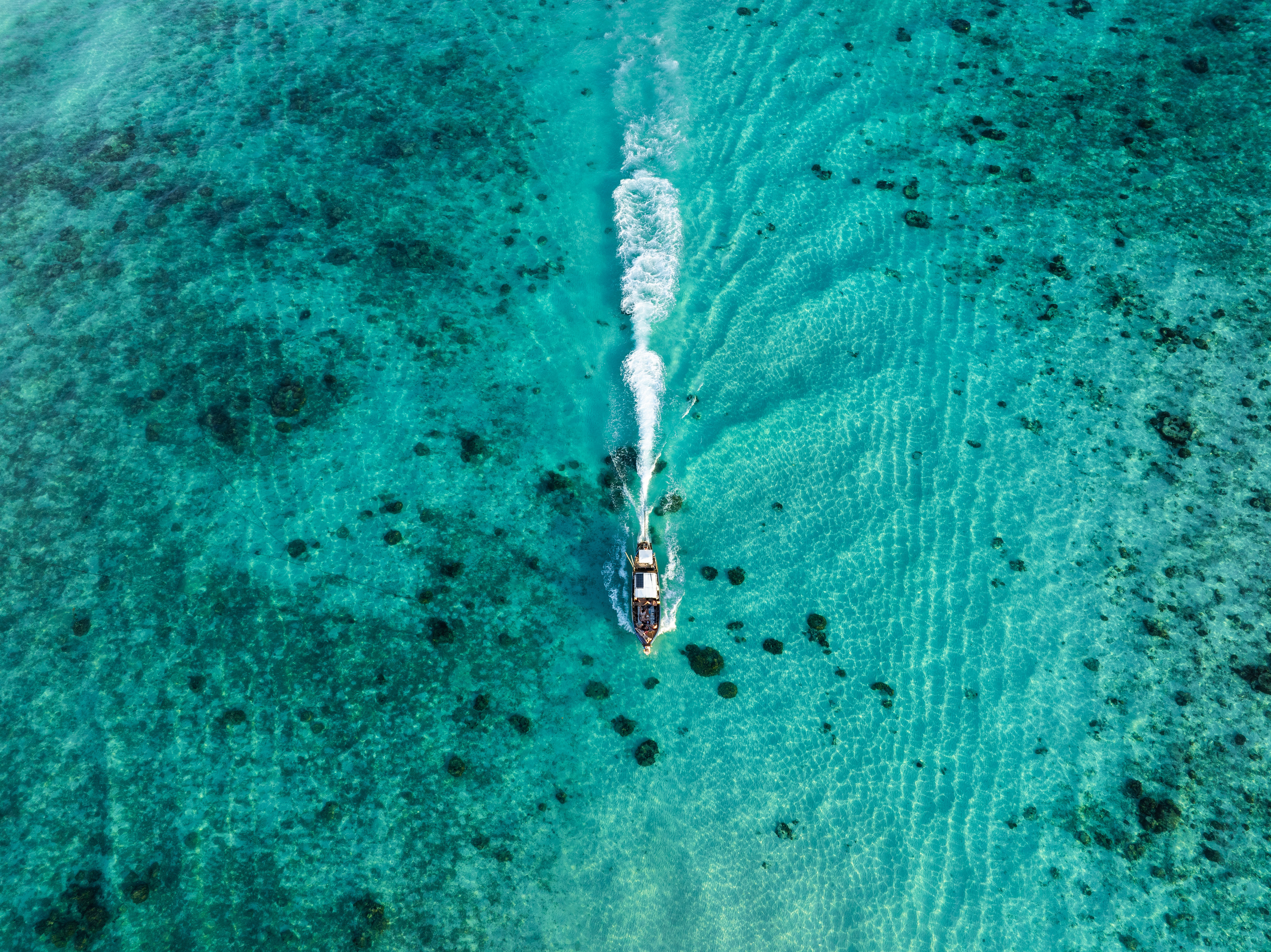 Aerial view of a boat cruising over turquoise Caribbean waters near Cahuita National Park, Costa Rica, heading to snorkeling and island tour