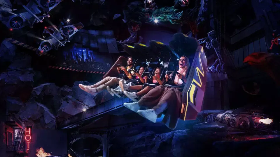 A family smiles while riding a suspended indoor dark ride vehicle through a rocky nighttime cityscape set at Warner Bros. World Abu Dhabi Theme Park.