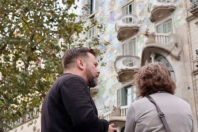 The tour guide is explaining the guest legends connect to the building of Casa Batlló in front of them